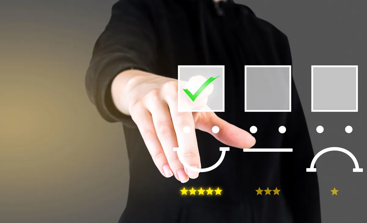 Hand selecting a smiling face with a five-star rating over neutral and unhappy options