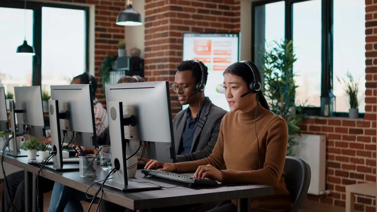 Customer support team working at computers with headsets in a bright office